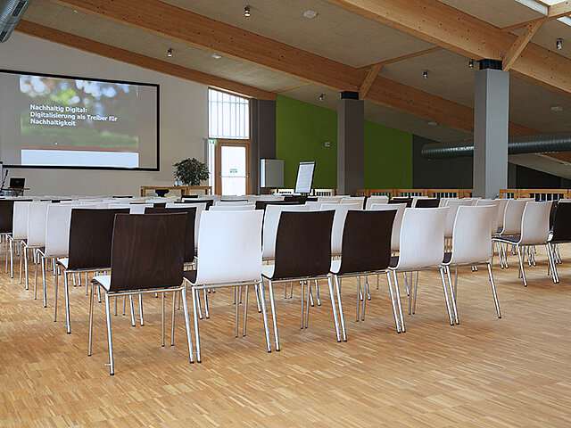 Im Konferenzraum sind Stühle, Tisch und eine Leinwand für Präsentationen vorhanden.
